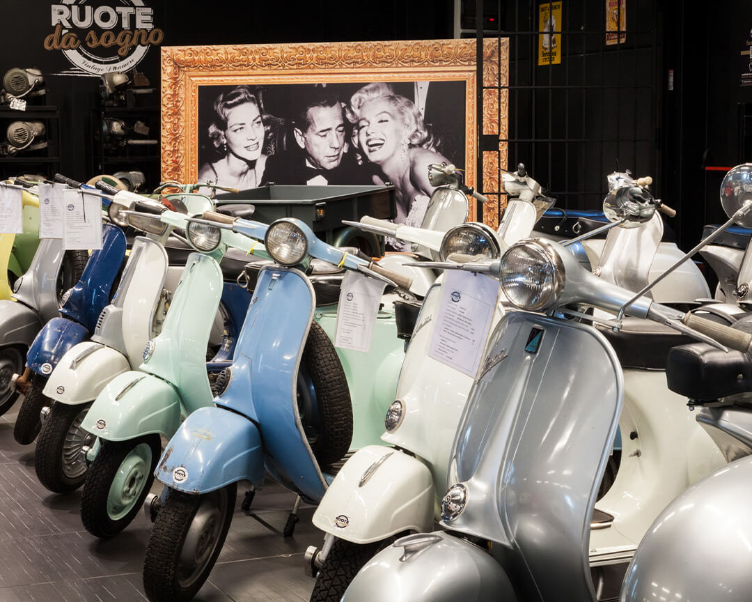 An array of vintage Vespas parked side by side in an exhibition hall of Ruote da Sogno