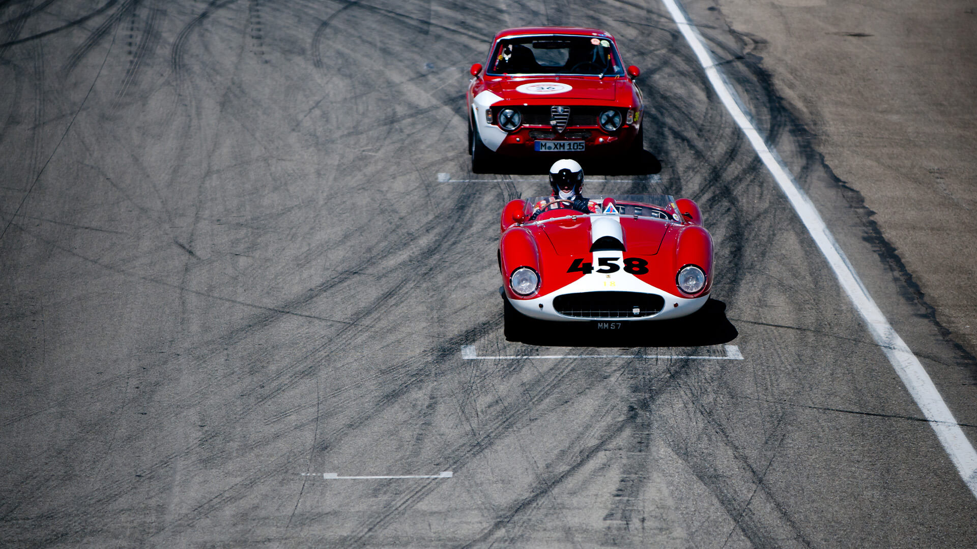 due auto rosse d'epoca su circuito con segni di pneumatici