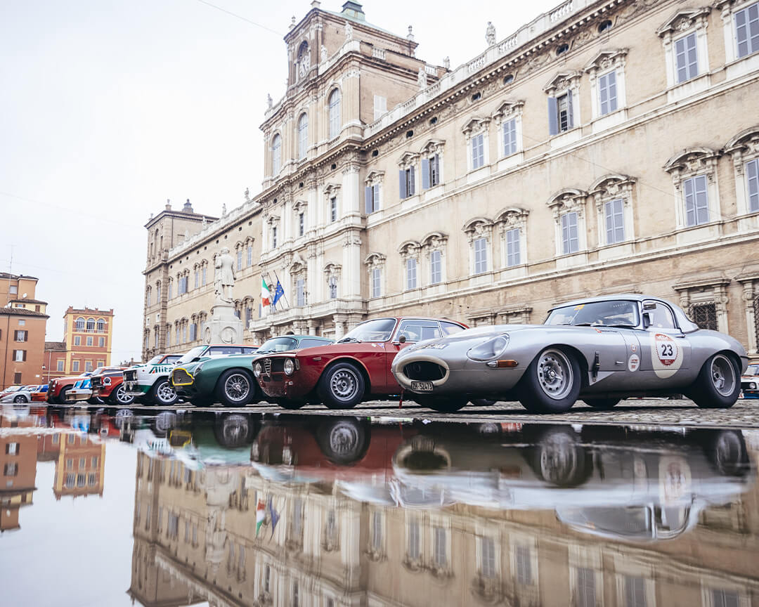auto d'epoca parcheggiate una accanto all'altra riflesse su specchio d'acqua