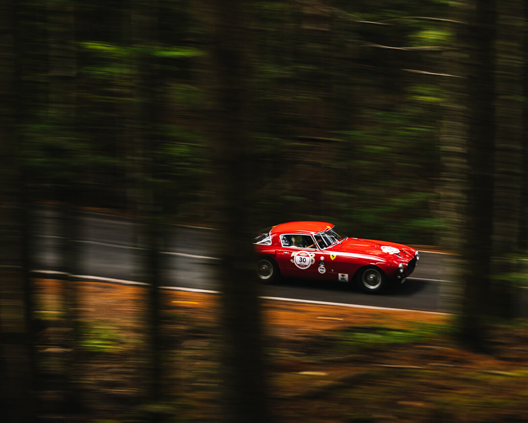 ferrari rossa d'epoca che sfreccia nel bosco