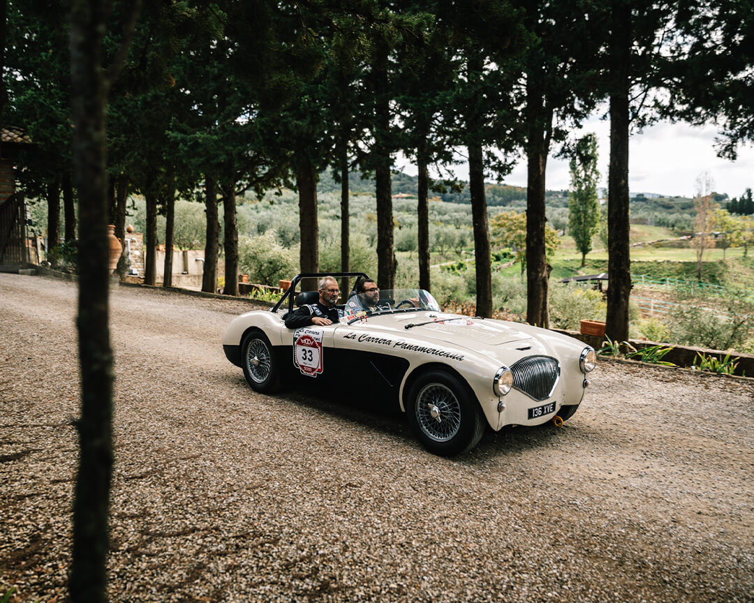 auto d'epoca cabrio bainca e nero su strada sterrata in campagna