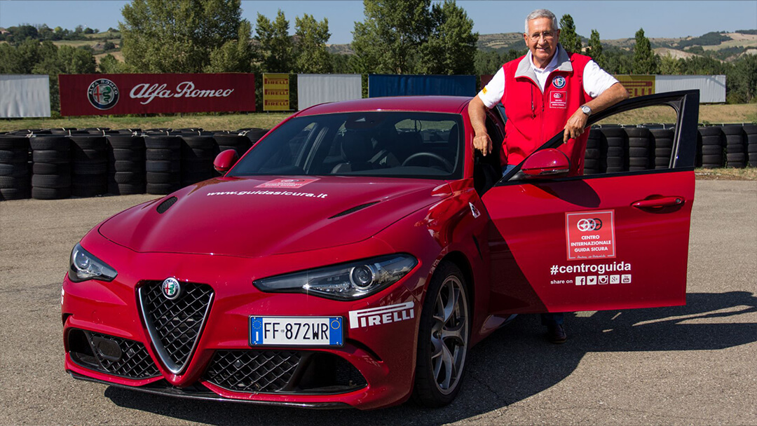Andrea De Adamich affianco ad una giulia quadrifoglio rossa del centro internazionale guida sicura