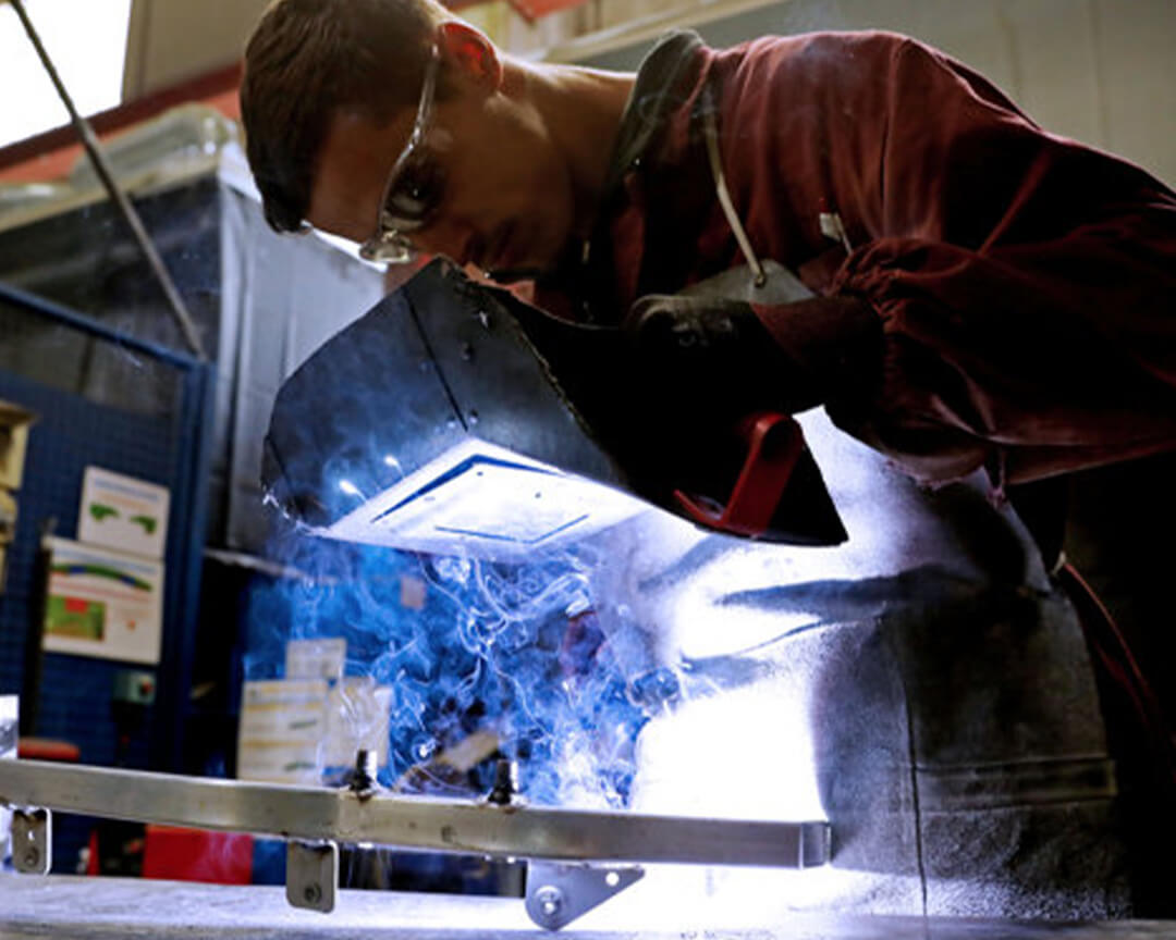 A vaccari e bosi worker, using a welding mask and the appropriate seal, welds a part of a car frame
