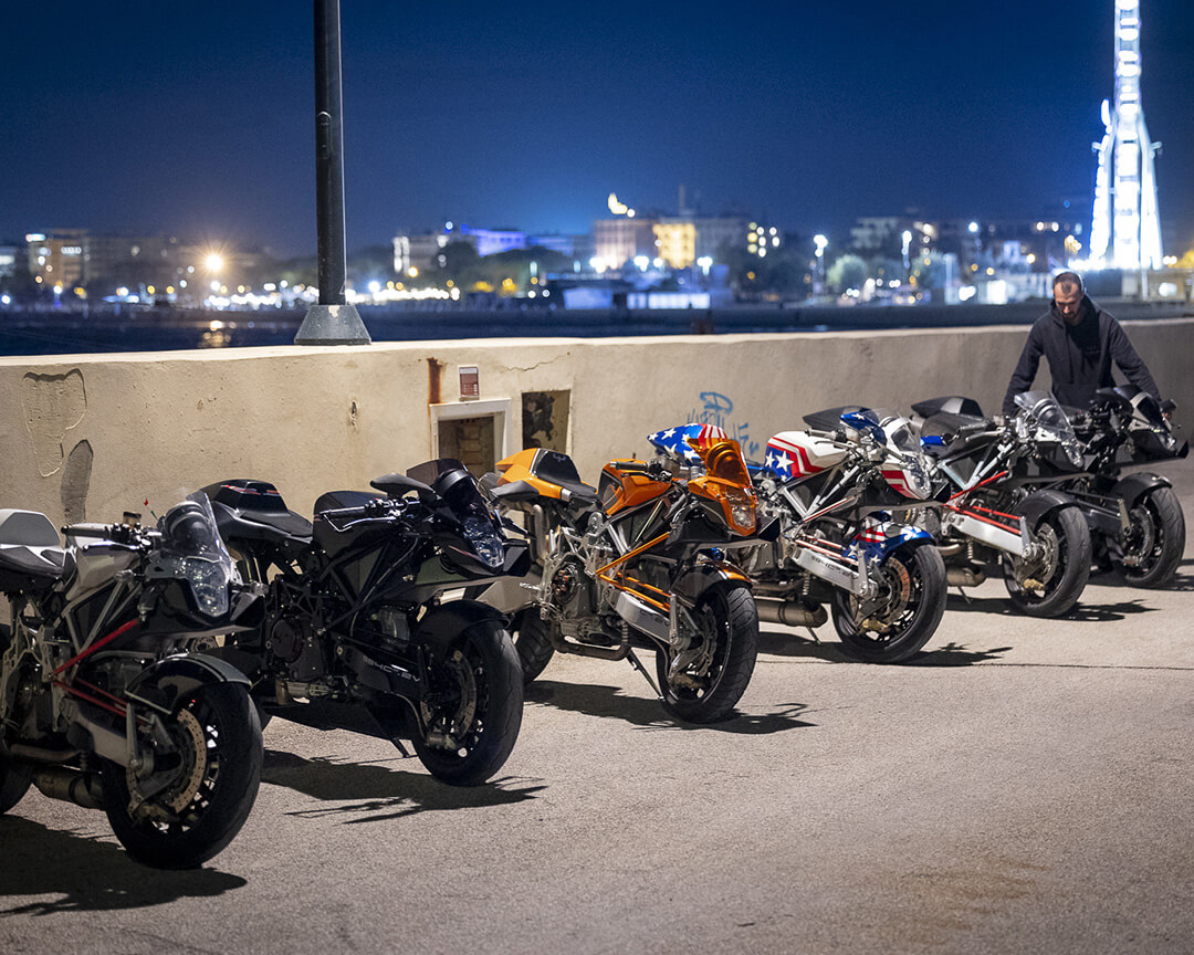 moto parcheggiate in fila di notte con skyline della città illuminata dietro
