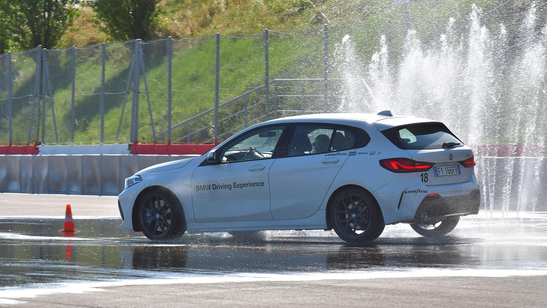 White BMW taking on tricky maneuvers on wet asphalt during a GuidarePilotare course
