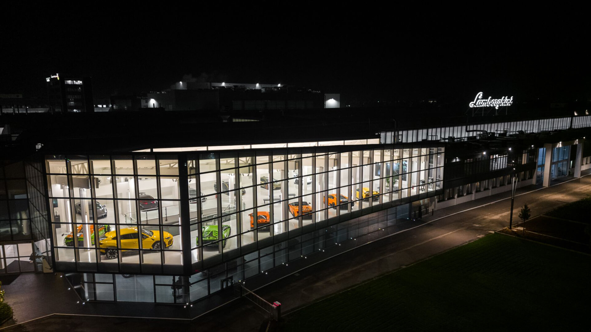 foto dall'alto del museo Lamborghini di notte con macchine illuminate e insegna Lamborghini sopra la stuttura illuminata