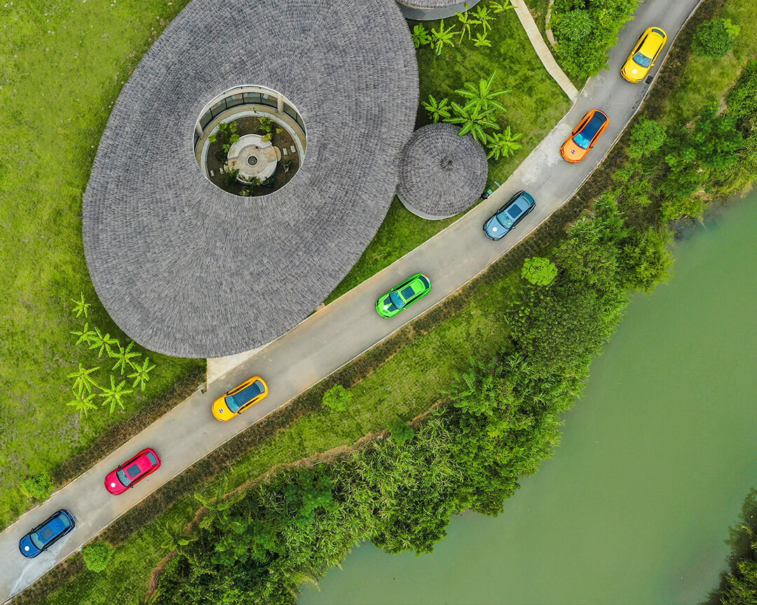 vista dall'alto di sfilata di auto Lamborghini di diversi colori nella natura vicino ad un fiume