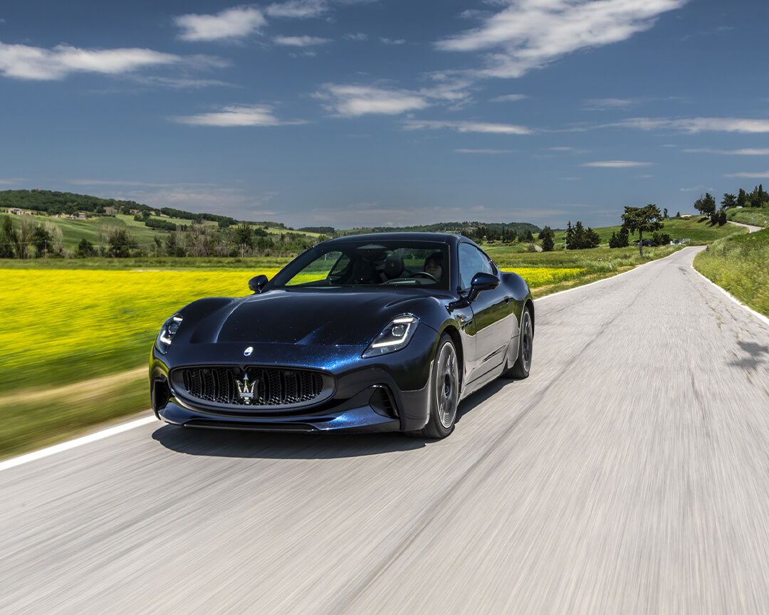 berlina maserati blu su strada asfaltata nelle colline dell'appennino