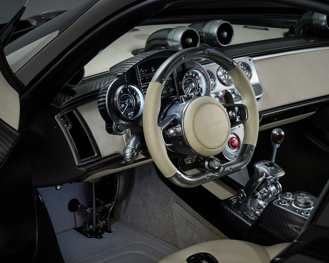 Abitacolo con cruscotto e volante e con interni bianchi di una vettura pagani