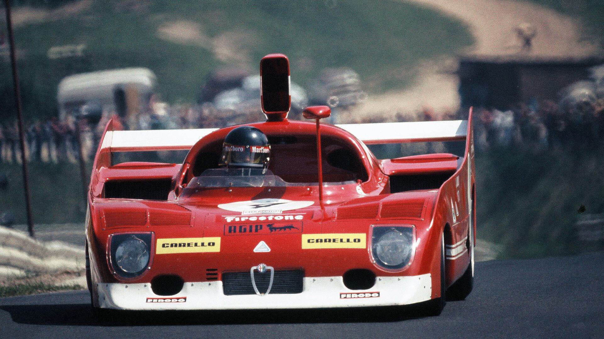 Una vecchia foto a colori ritrae una vettura da scalata alfa romeo che affronta un tracciato