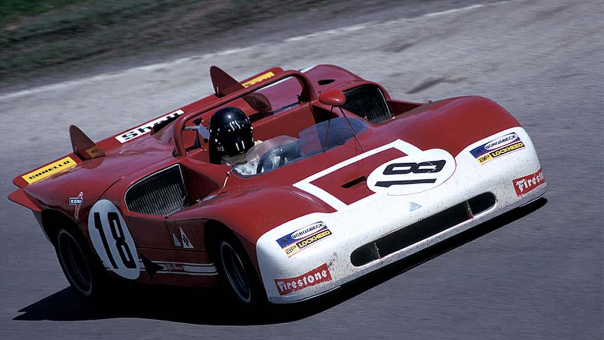 Una vecchia foto a colori ritrae una vettura da scalata alfa romeo con il numero 18 che affronta un tracciato