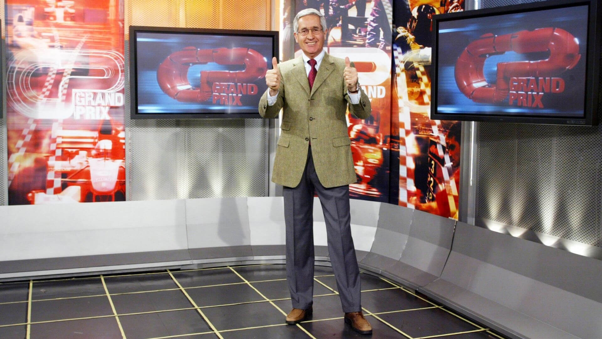 Andrea de adamich che con i pollici alzati all'interno dello studio Grand prix