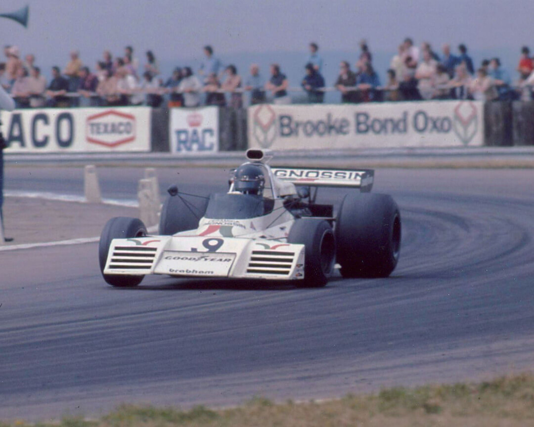 Una vecchia foto a colori ritrae una monoposto d'epoca che affronta una curva di un tracciato