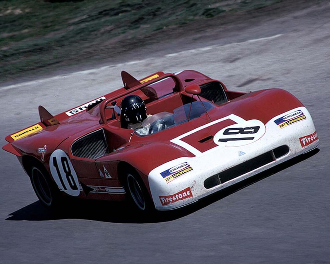 Una vecchia foto a colori ritrae una vettura da scalata alfa romeo con il numero 18 che affronta un tracciato