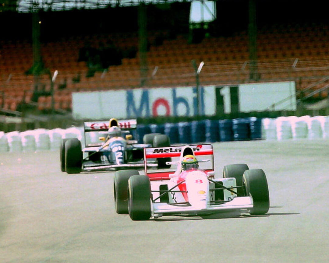 a white and red McLaren, driven by Ayrton Senna, leading a Williams on the circuit during a Formula 1 race.