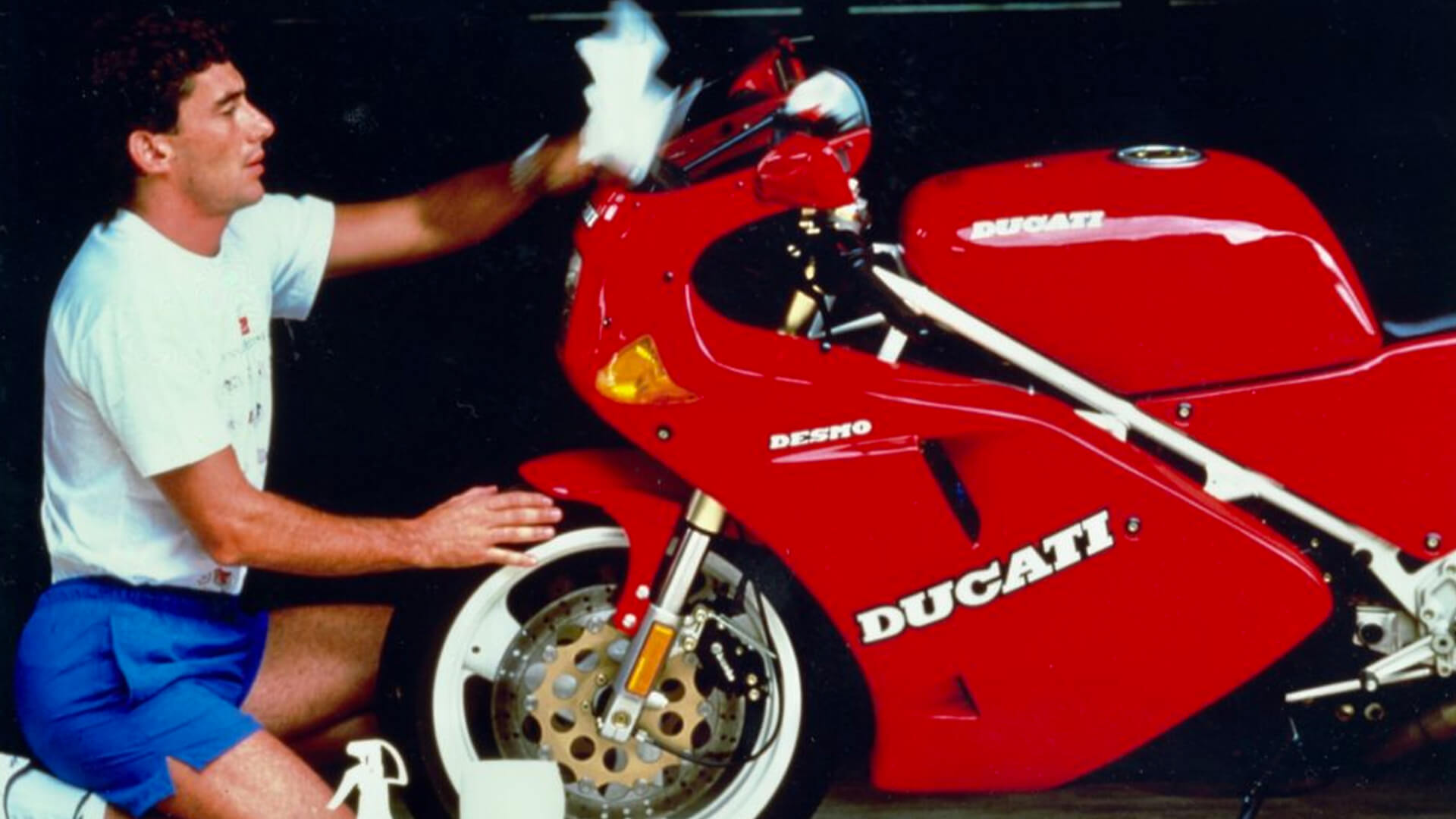 vecchia foto a colori di senna che pulisce la sua ducati desmo rossa con cerchi bianchi