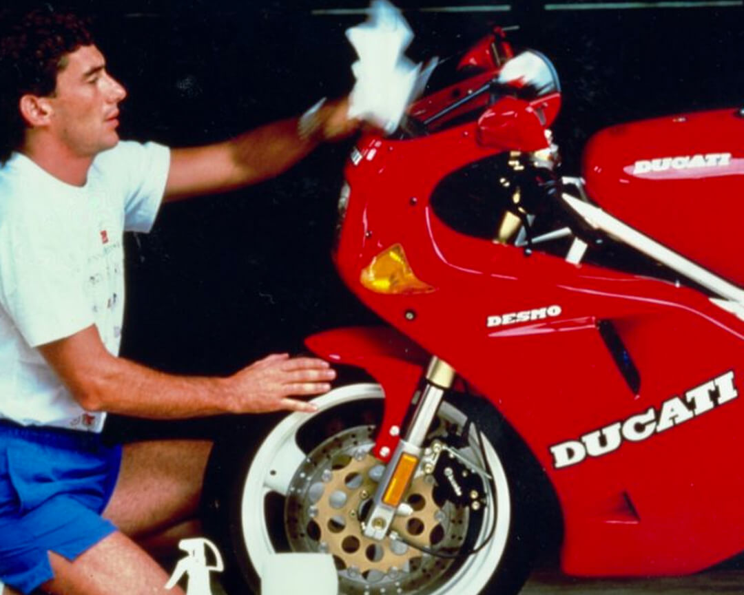 vecchia foto a colori di senna che pulisce la sua ducati desmo rossa con cerchi bianchi