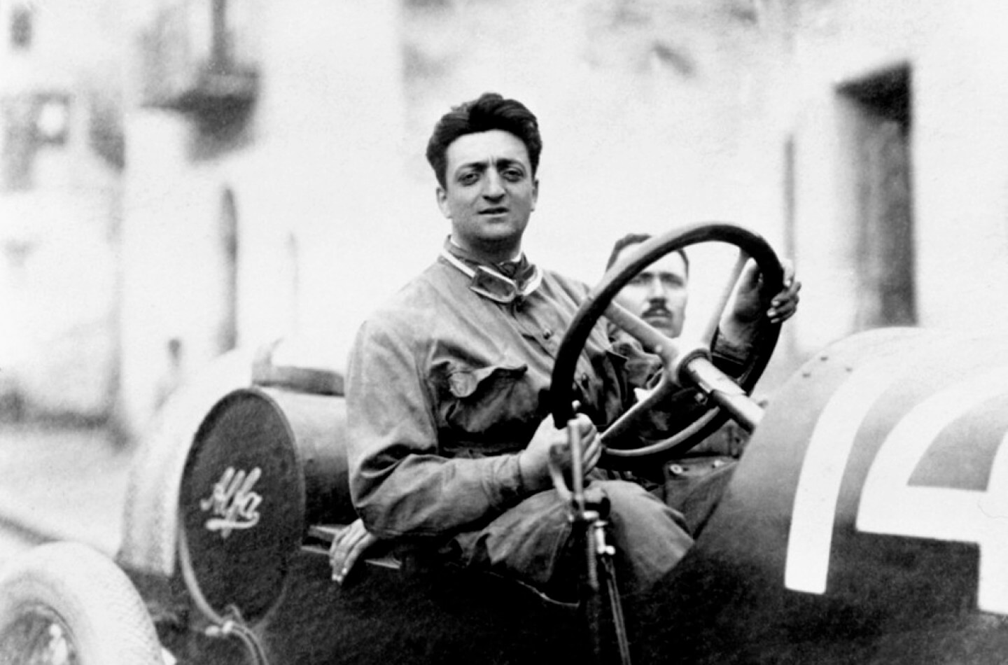 foto di Enzo Ferrari da giovane in bianco e nero alla guida di un'auto d'epoca