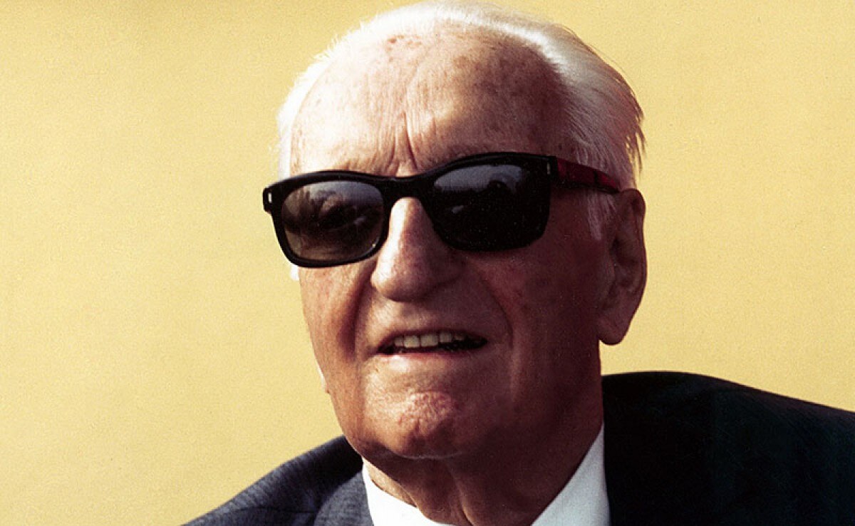 Foto di Enzo Ferrari con occhiali da sole su sfondo giallo