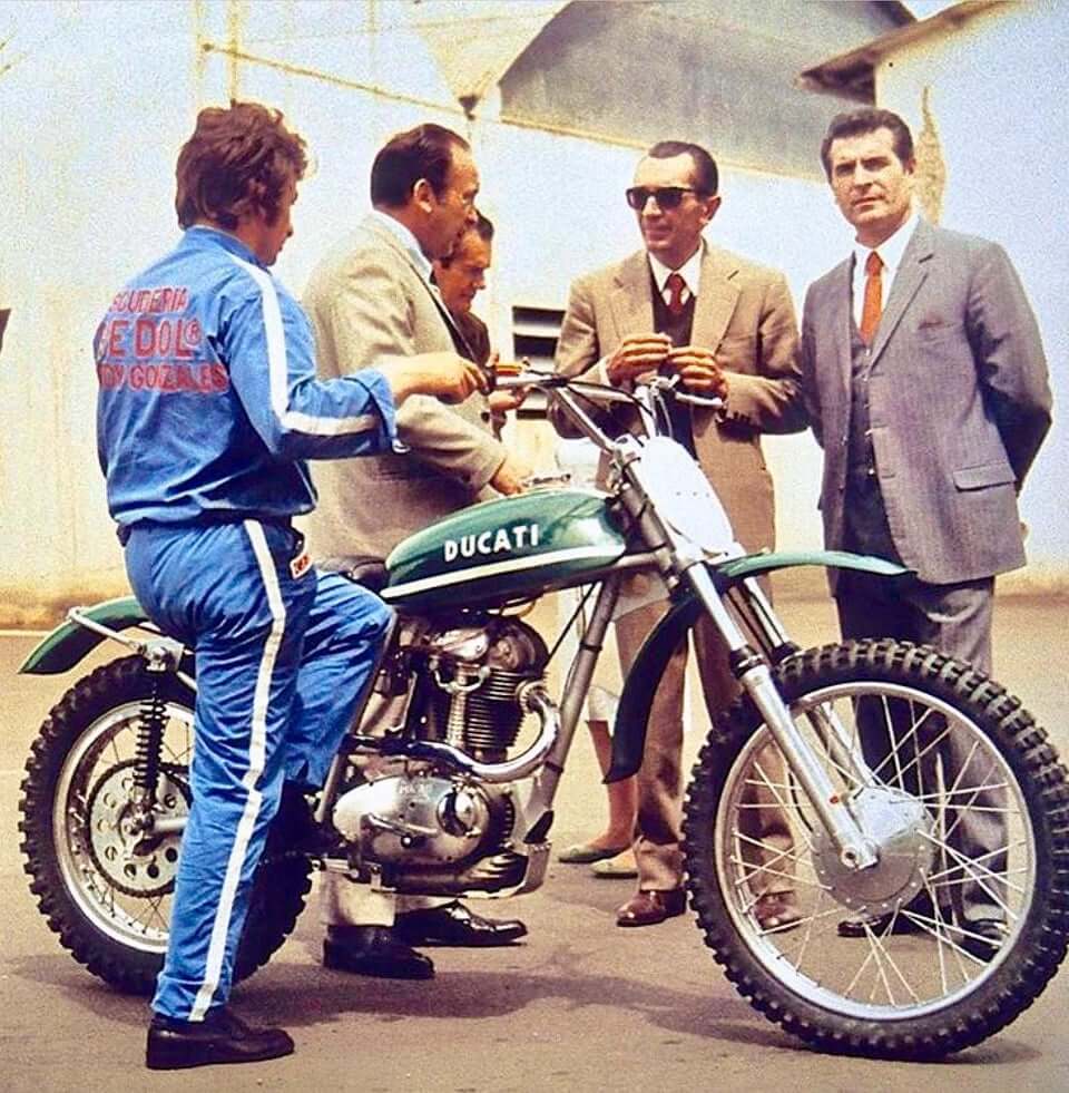 in una vecchia foto a colori, ingegneri e meccanici attorno ad una moto ducati discutono, tra questi anche fabio taglioni