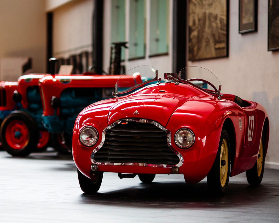 All'interno del museo ferruccio lamborghini si vede una macchina giocattolo rossa affianco a dei trattori lamborghini giocattolo