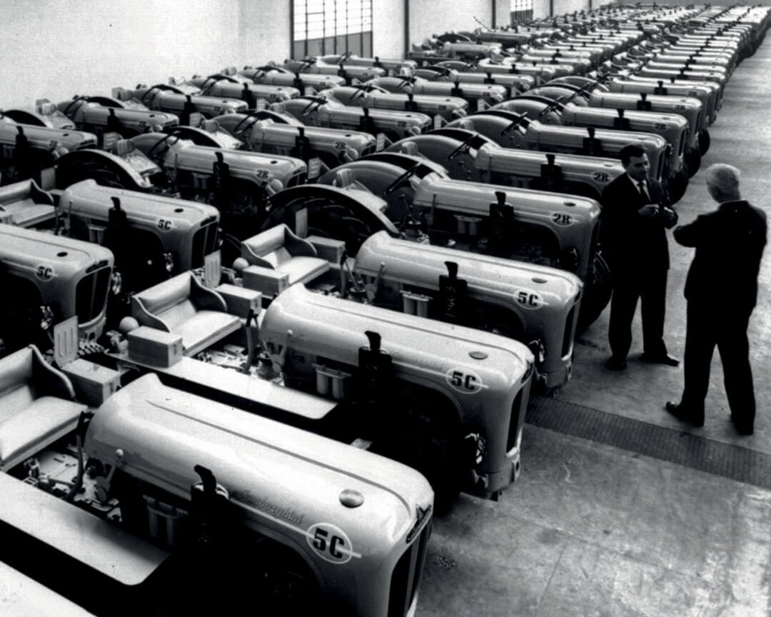 Una vecchia foto in bianco e nero che ritrae l'interno dello stabile industriale di lamborghini con al suo interno svariati trattori parcheggiati