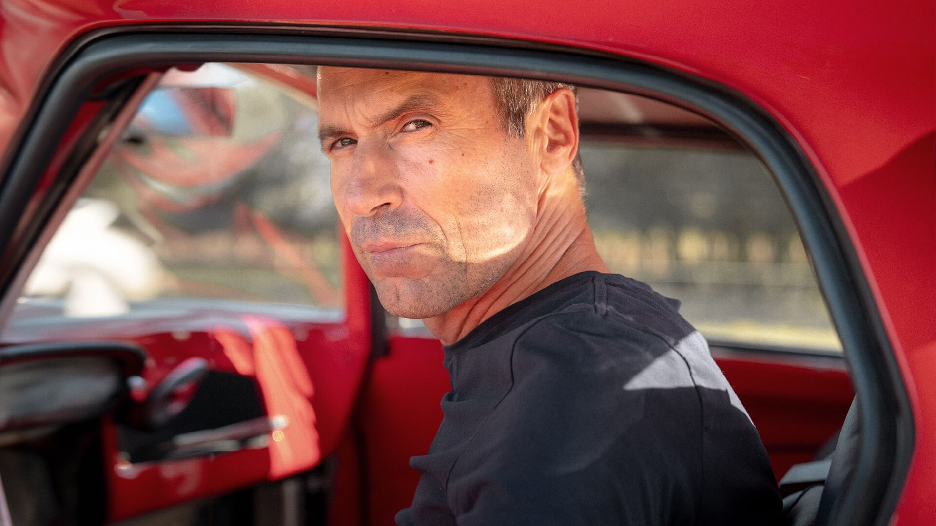 umberto panini fotografato all'interno di un auto rossa d'epoca
