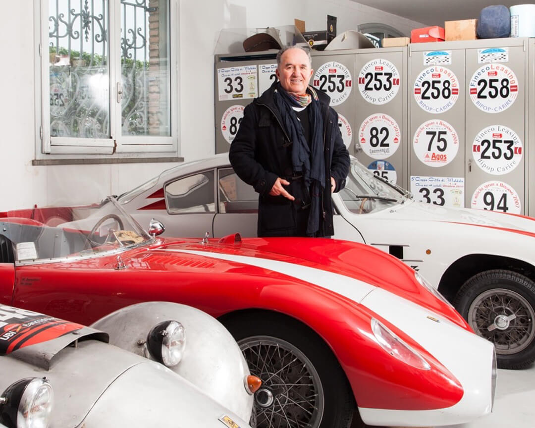 DIno Bandini, nipote di Ilario in piedi tra le auto rosse e biancorosse della collezione Bandini