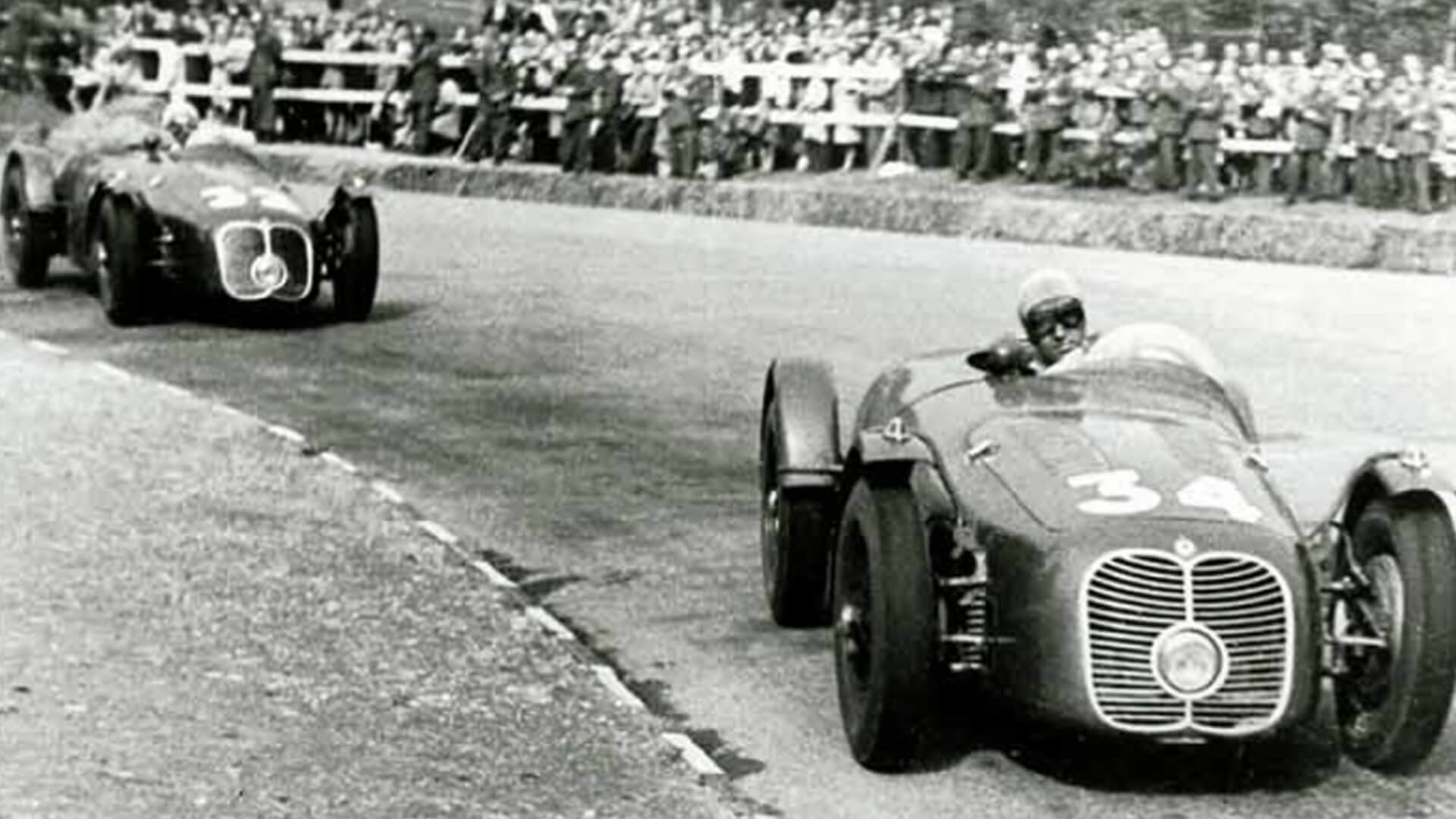 In una foto d'epoca in bianco e nero venecono ritratte due maserati d'epoca da competizione con il numero 34 e 32 me ntre affrontano una curva di un circuito