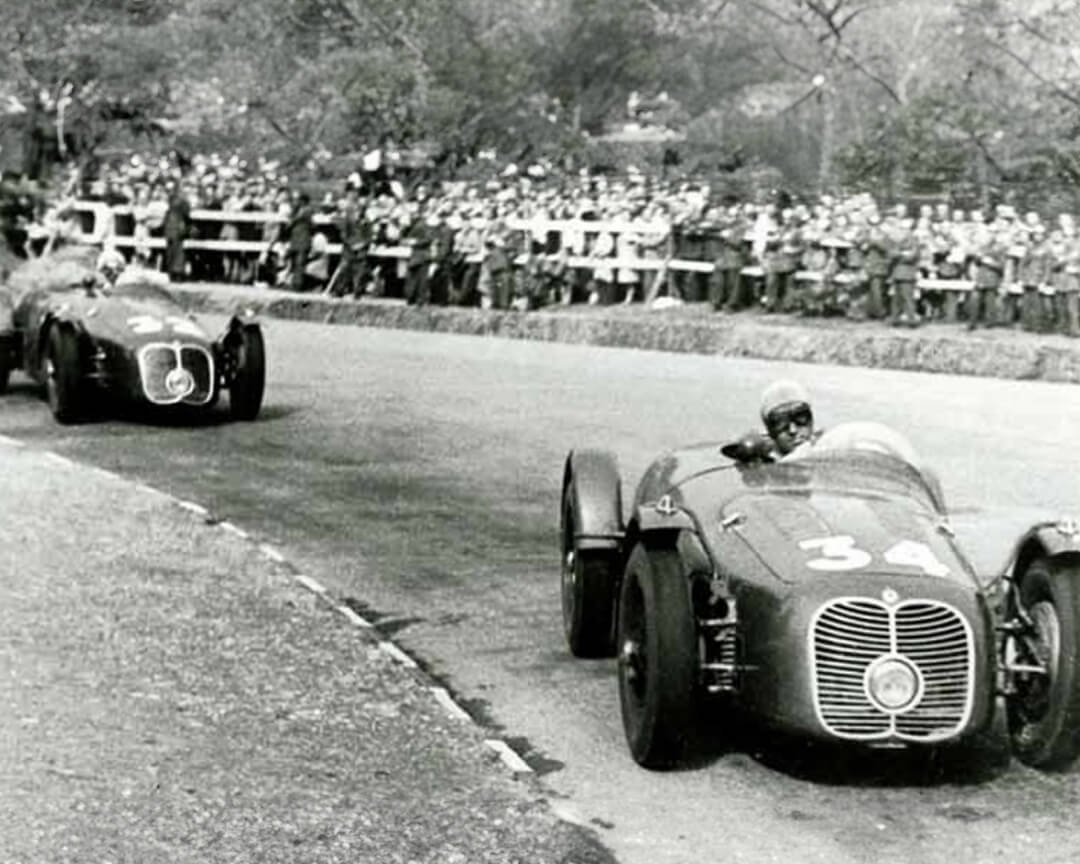 In una foto d'epoca in bianco e nero venecono ritratte due maserati d'epoca da competizione con il numero 34 e 32 me ntre affrontano una curva di un circuito