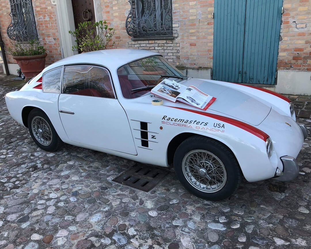 foto di Bandini GT 750 con dettagli rossi e la scritta scuderia bandini con libro di auto adagiato sopra e rotolo di scotch cartaa