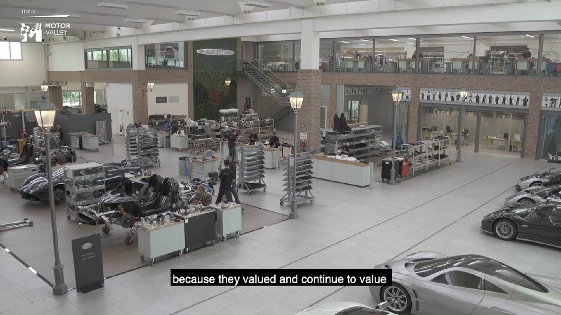 Foto della sede pagani vista dall'interno, con vetture pagani in costruzioni e i sottotitoli dell'intervista ad horacio pagani