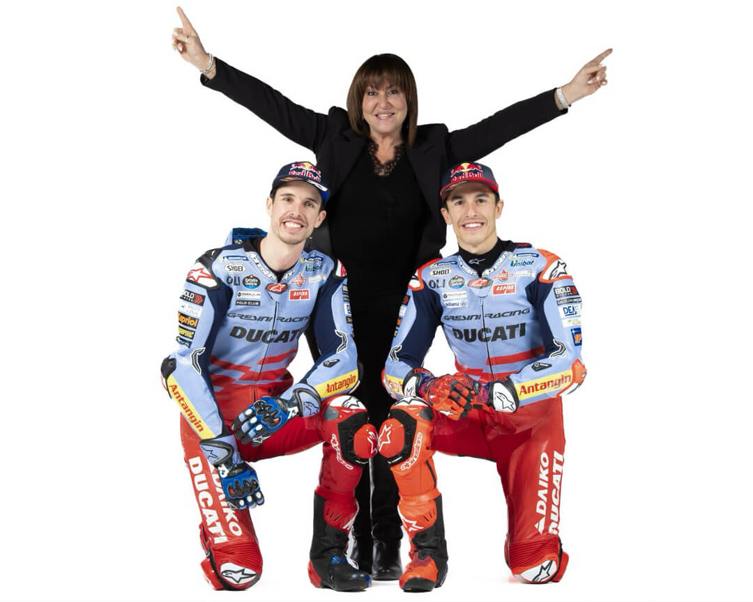 photo of Nadia Padovani in black dress with arms raised together Alex Marquez and Marc Marquez sitting on knee smiling