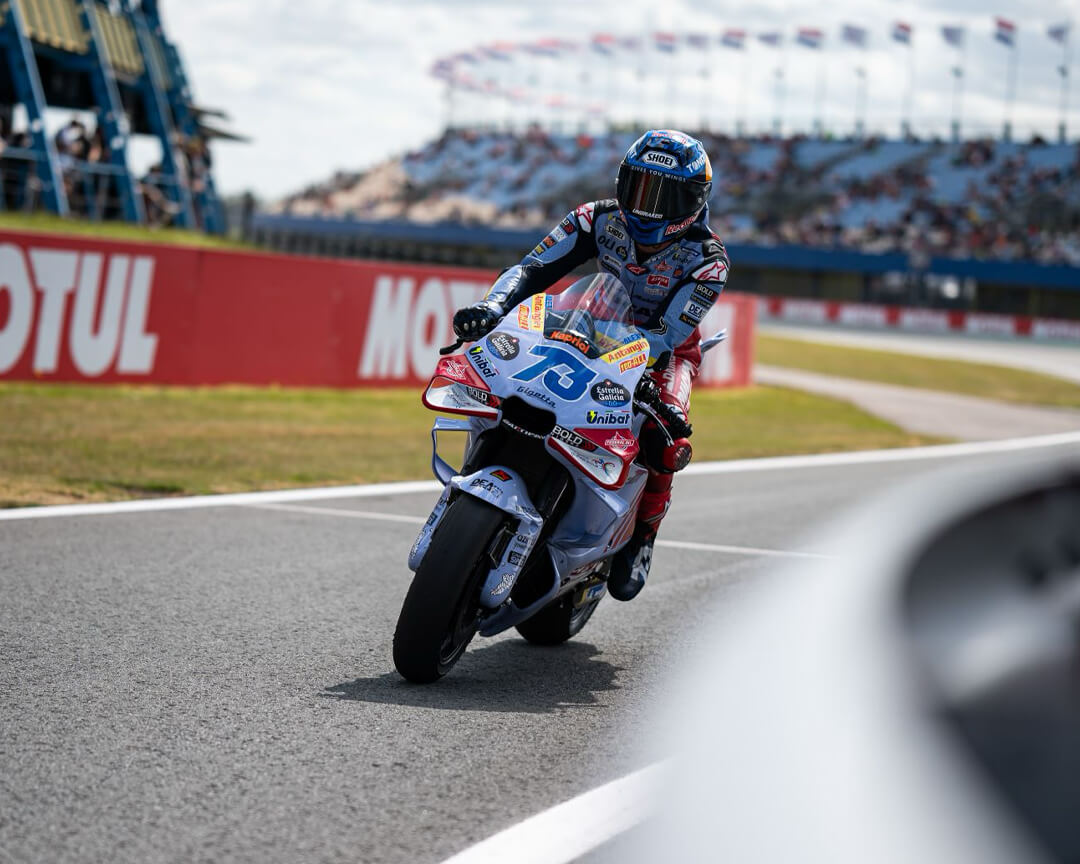 motogp rider on a race bike, on the track with the Motul sponsor in the background and an audience in the stands.