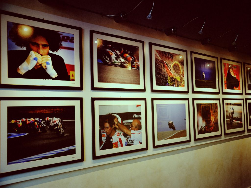 Una parete del museo allestita con due file di fotografie incorniciate che ritraggono il pilota Marco Simoncelli in vari momenti di gara, in curva e ai box.