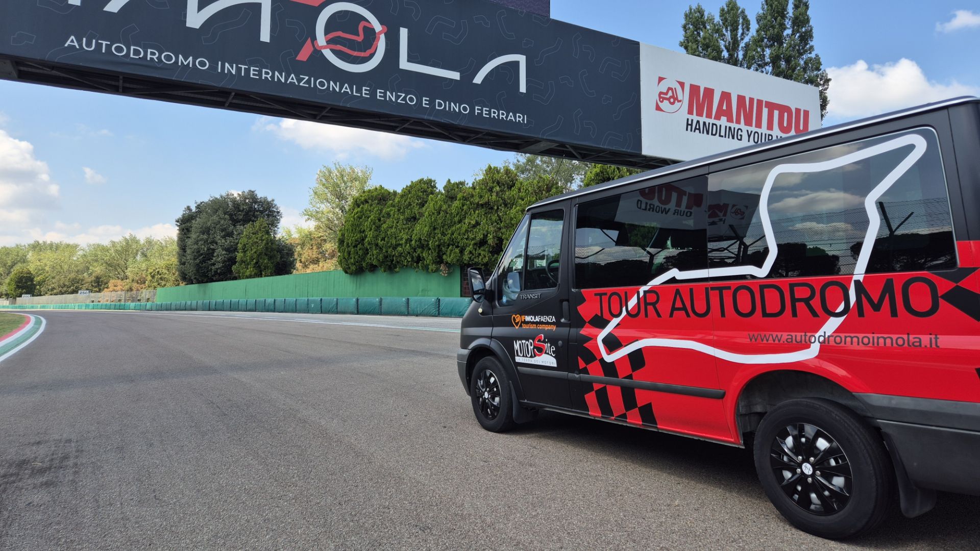 La navetta dell'Autodromo di Imola percorre la pista sotto un cartello con il logo dell'Autodromo.