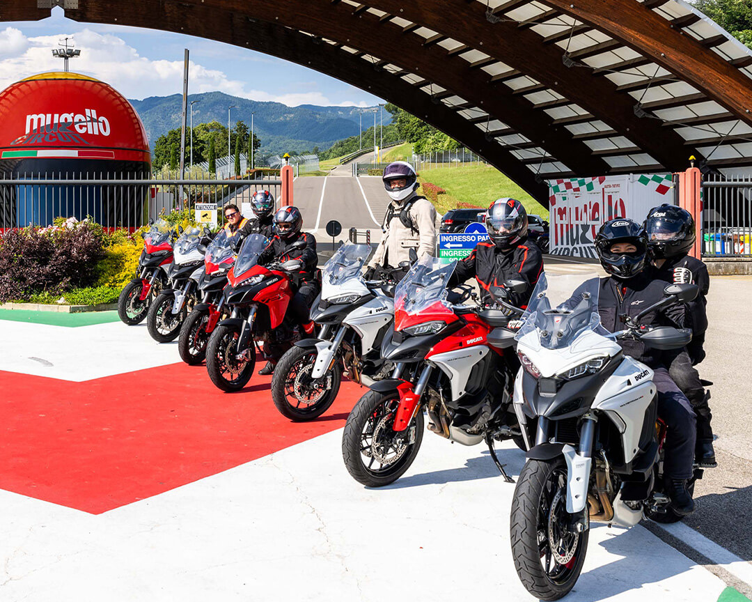 group of motorcyclists riding the ducati Multistrada in front of the entrance to the Mugello circuit