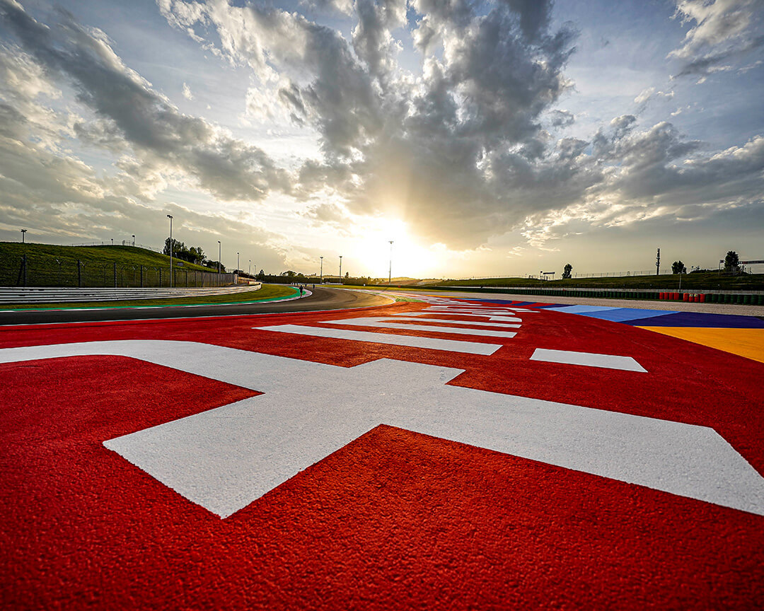 dettagli di un cordolo dell'asfalto del circuito di misano con il sole che sale sullo sfondo