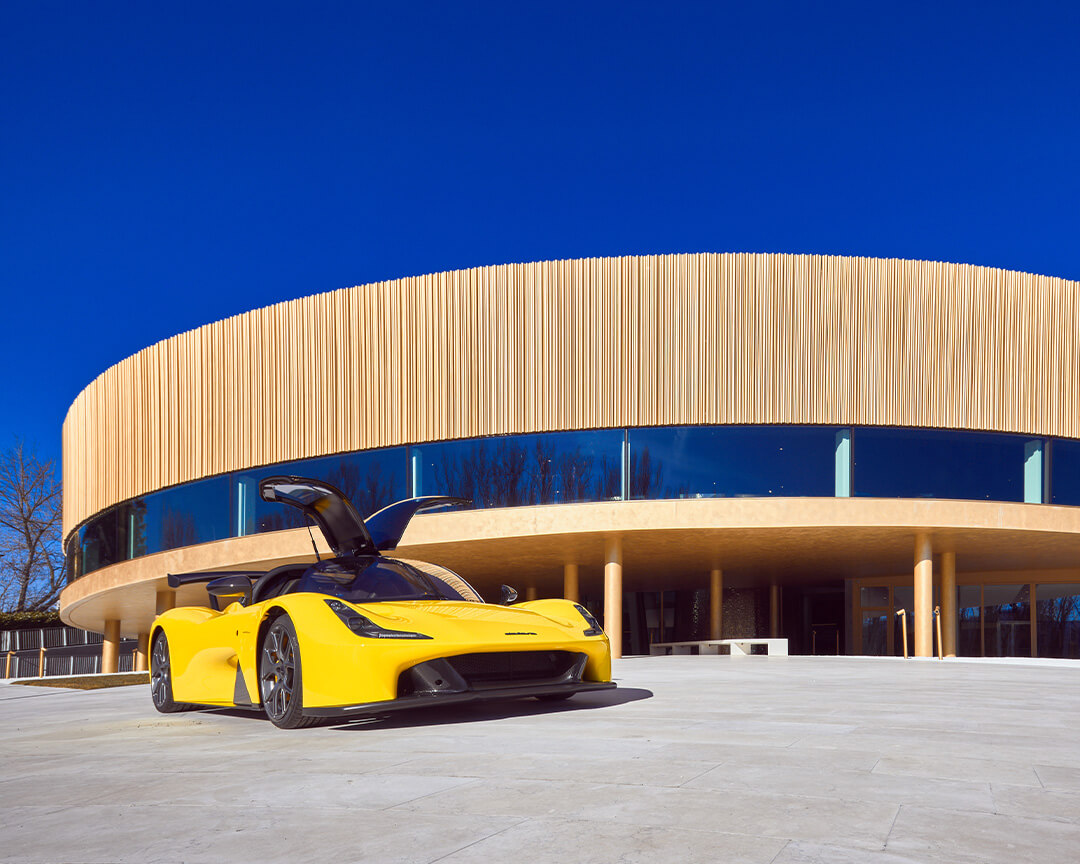Yellow Dallara Stradale with open doors that look like wings parked in front of the Academy