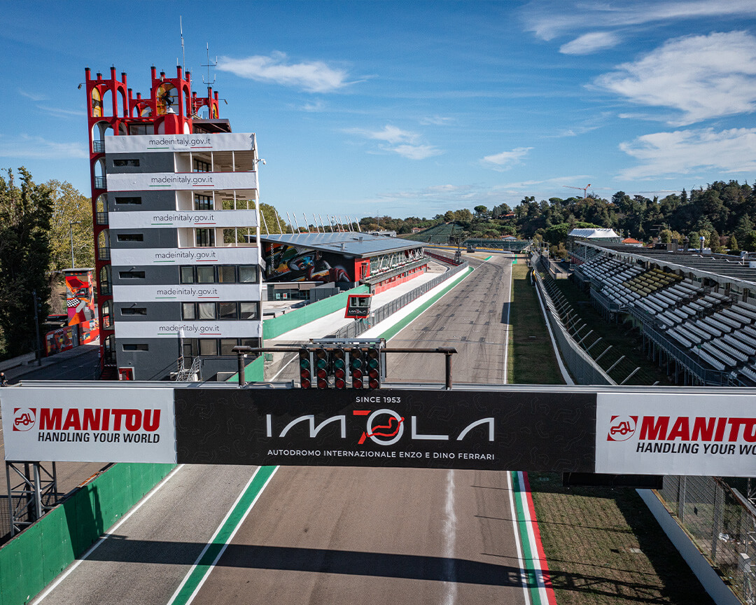 foto aerea dei box del circuito di Imola con la scritta e i logo imola, la torre e gli spalti