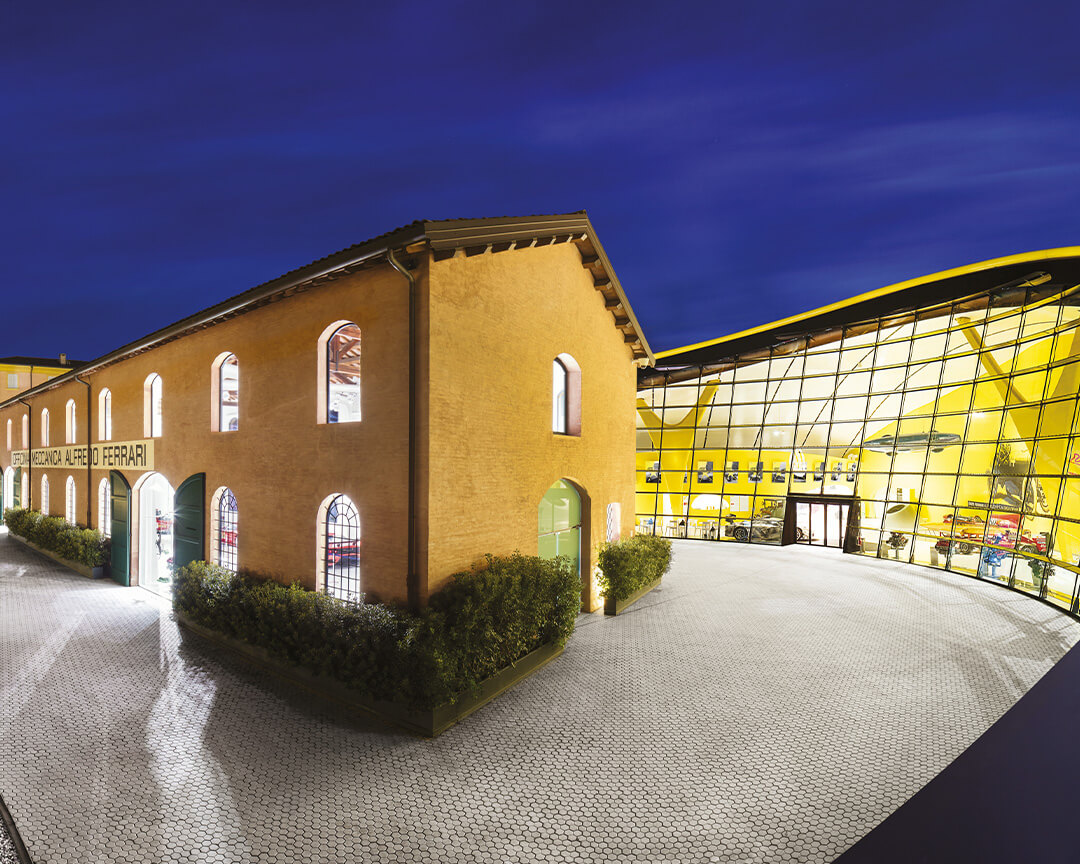 Evening panoramic view of the entire Enzo Ferrari museum with the new pavilion grafting into the old machine shop building