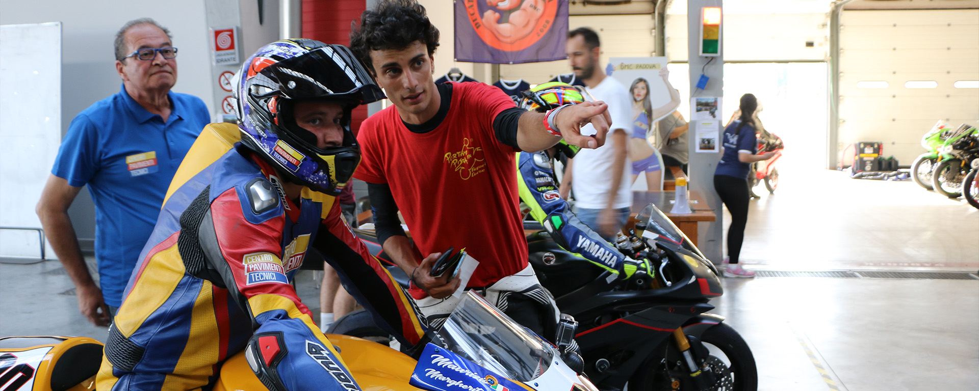 motociclista in tuta e operatore all'interno di un box