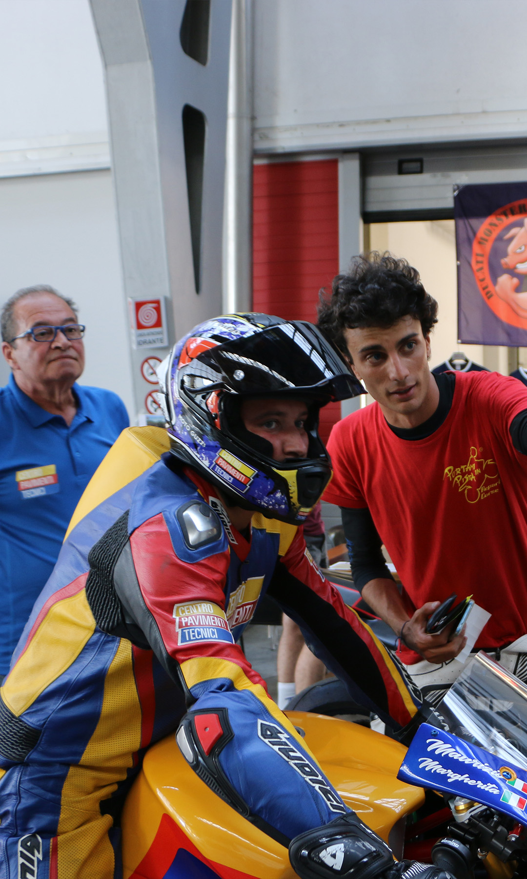 motociclista in tuta e operatore all'interno di un box