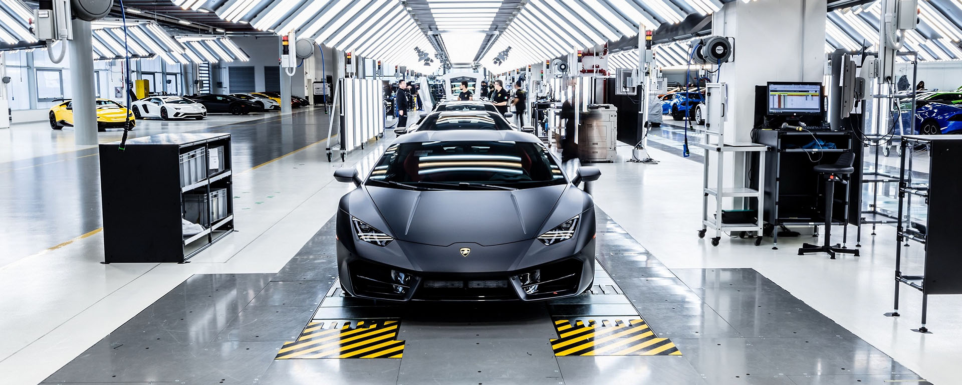 Automobile Lamborghini Aventador nera all'interno del tunnel di controllo qualità e finissaggio con luci al neon verticali