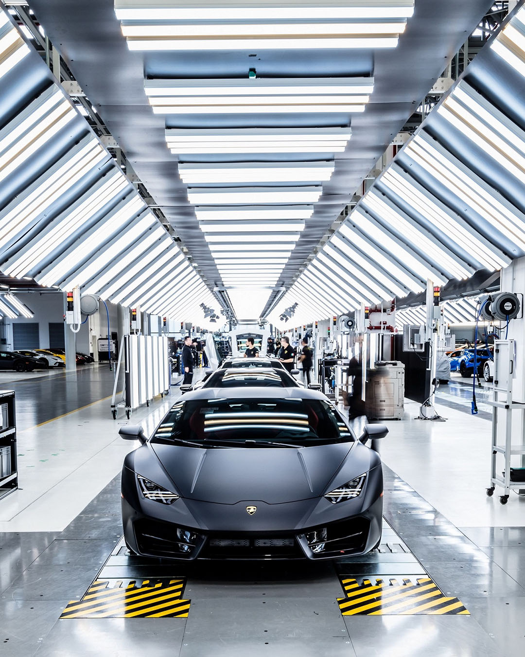Automobile Lamborghini Aventador nera all'interno del tunnel di controllo qualità e finissaggio con luci al neon verticali