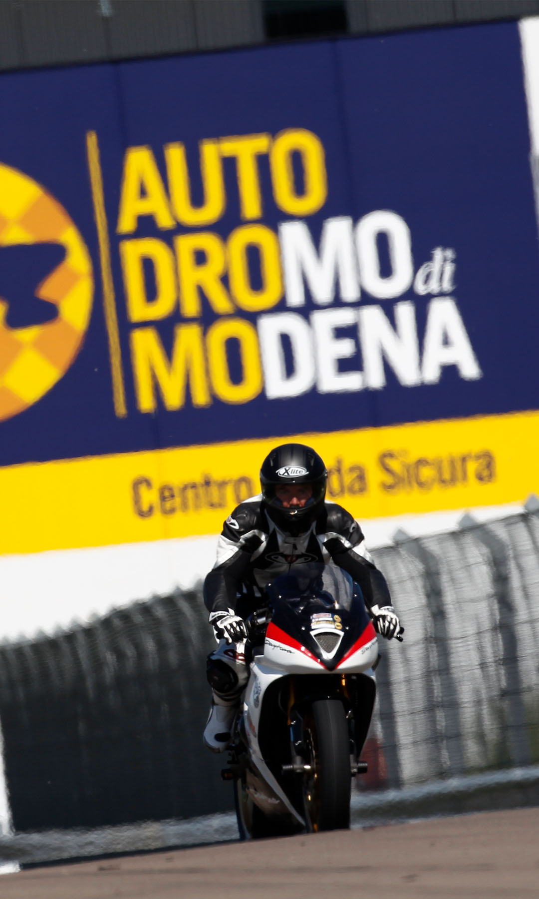 Moto in pista nell'autodromo di Modena con banner dietro.