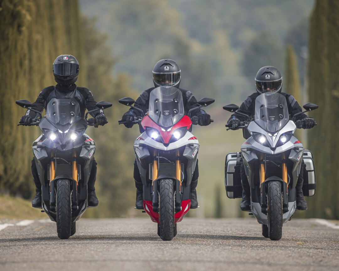 three energica bikes one beside the other run along. a tree-lined road