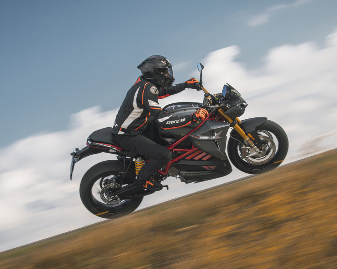 An energica test driver riding a black-colored rebel faces a high-speed curve