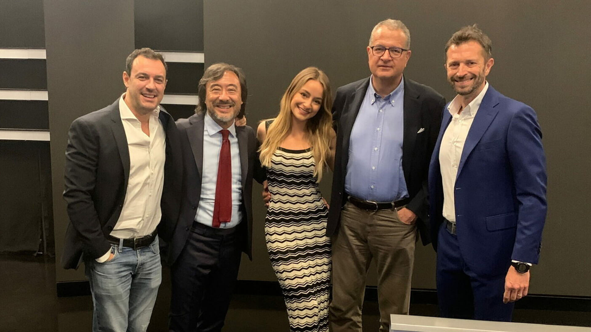 photo of Carolina Tedeschi in the company of gentlemen in a suit and tie looking at the lens smiling