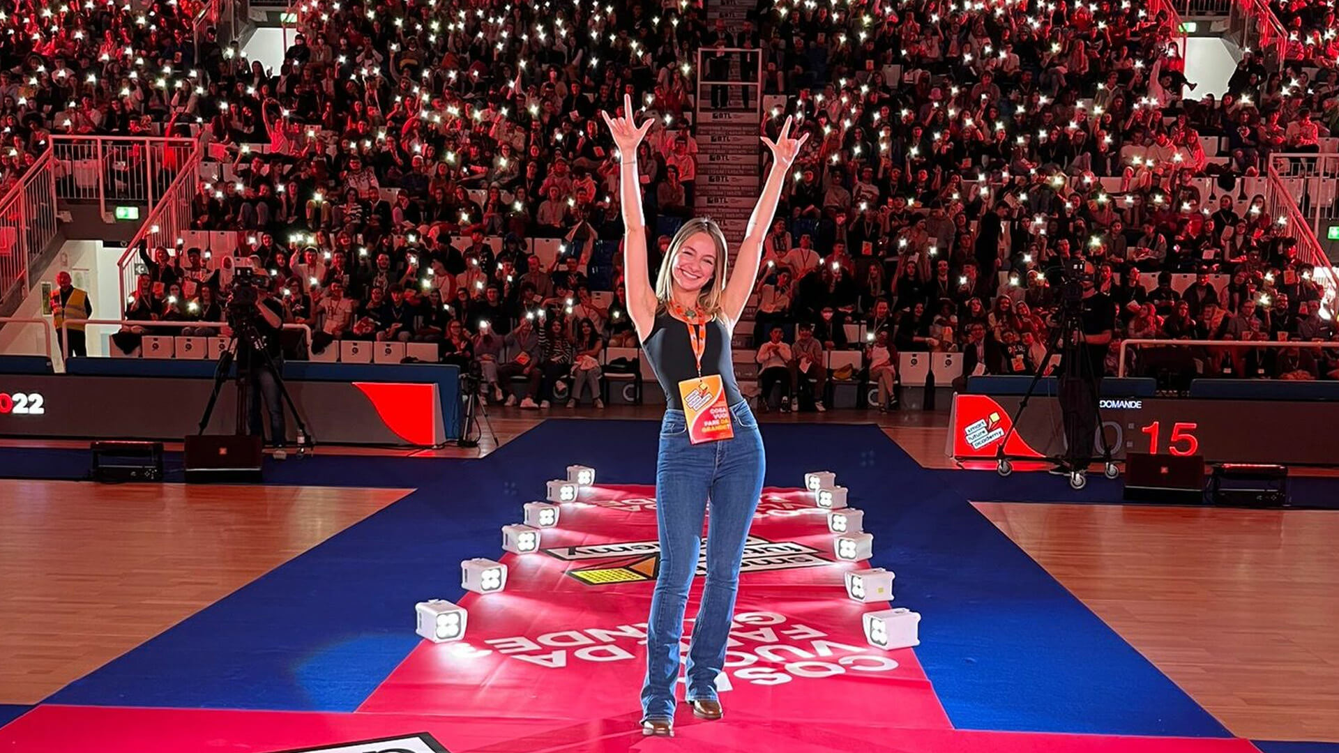 photos of Carolina Tedeschi standing with arms raised that make the symbol of rock with people on the stands holding torches in their hands